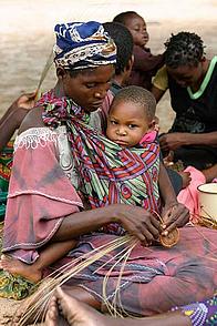 Local woman with child crafting handicraft goods. Namibia.