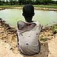 A boy sits on the ground while overlooking a dam built by his village. Lake Bogoria, Kenya