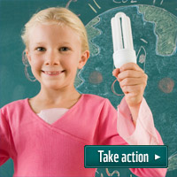 Keep climate change in the curriculum - (c) iStock Girl holds low energy lightbulb in front of chalkboard - 'Take Action'.