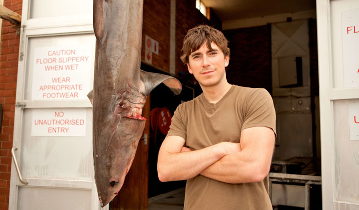 Simon Reeve with a dead juvenile Great White Shark, at the headquarters of the Natal Sharks Board in South Africa. © ANDREW CARTER Simon Reeve with a dead juvenile Great White Shark, at the headquarters of the Natal Sharks Board in South Africa. © ANDREW CARTER