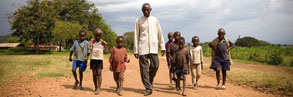 Mbiwo Constantine Kusebahasa walking to his farm with his grandchildren and local children, Uganda