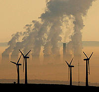 Steam rises from a power station behind a wind farm 