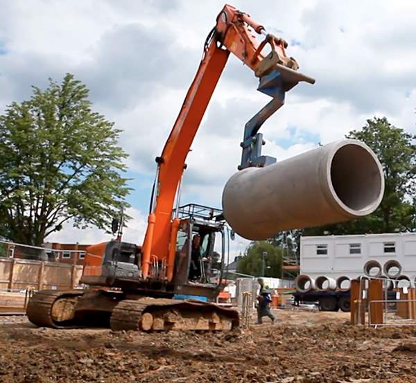 Part of the concrete earth duct tubing being lowered into position onsite